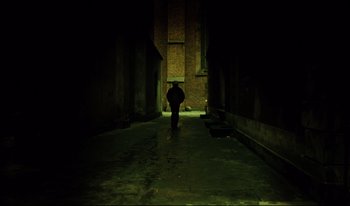 Movie still from “A Short Film About Killing” (1988), directed by Krzysztof Kieslowski – A person walking down a dark alley at night; Extreme Wide shot, Low angle