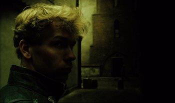 Movie still from “A Short Film About Killing” (1988), directed by Krzysztof Kieslowski – A man with blonde hair is standing in a dark room; Close Up shot, Low angle