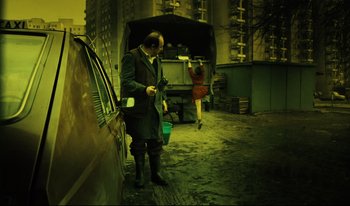 Movie still from “A Short Film About Killing” (1988), directed by Krzysztof Kieslowski – A man standing next to a woman in a red dress; Wide shot, Low angle