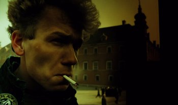 Movie still from “A Short Film About Killing” (1988), directed by Krzysztof Kieslowski – A man smoking a cigarette in front of a building; Close Up shot, Low angle
