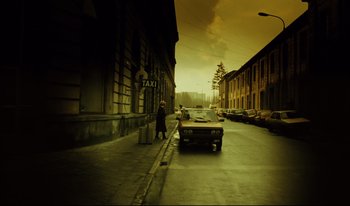 Movie still from “A Short Film About Killing” (1988), directed by Krzysztof Kieslowski – A taxi cab parked on the side of the street; Extreme Wide shot, Low angle