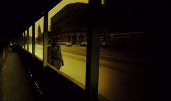 Movie still from “A Short Film About Killing” (1988), directed by Krzysztof Kieslowski – A man standing in front of a window with cars on the street; Wide shot, Low angle