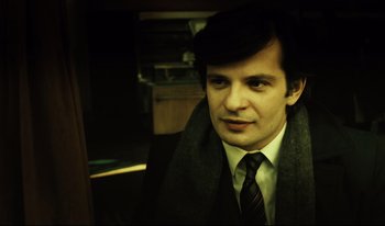 Movie still from “A Short Film About Killing” (1988), directed by Krzysztof Kieslowski – A man wearing a suit and tie with a scarf around his neck; Close Up shot, High angle