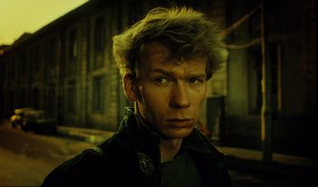 Movie still from “A Short Film About Killing” (1988), directed by Krzysztof Kieslowski – A young man with spiky blonde hair stares into the camera; Close Up shot, Low angle