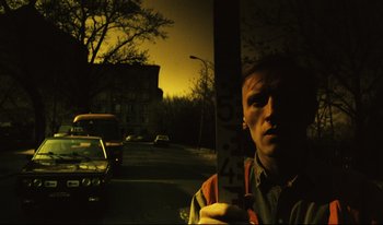 Movie still from “A Short Film About Killing” (1988), directed by Krzysztof Kieslowski – A man standing in front of a street sign in the dark; Close Up shot, Low angle