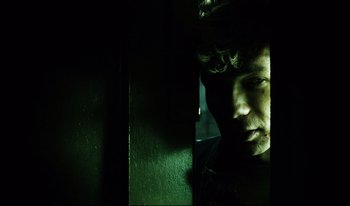 Movie still from “A Short Film About Killing” (1988), directed by Krzysztof Kieslowski – A man in a dark room looking at the camera; Close Up shot, Low angle