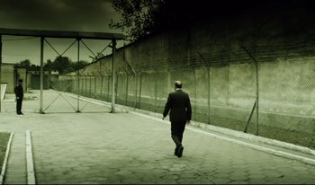 Movie still from “A Short Film About Killing” (1988), directed by Krzysztof Kieslowski – A man in a suit walking down a sidewalk; Wide shot, Low angle