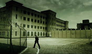 Movie still from “A Short Film About Killing” (1988), directed by Krzysztof Kieslowski – A person walking in front of an old building; Extreme Wide shot, Low angle