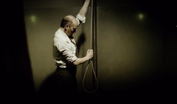 Movie still from “A Short Film About Killing” (1988), directed by Krzysztof Kieslowski – A man holding onto a rope with one hand and one hand on the other; Medium shot, Low angle
