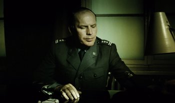 Movie still from “A Short Film About Killing” (1988), directed by Krzysztof Kieslowski – A man in a uniform sitting in front of a window; Medium shot, Low angle