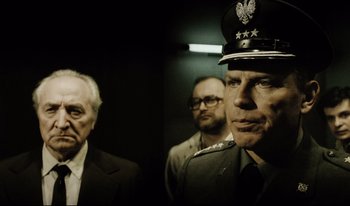 Movie still from “A Short Film About Killing” (1988), directed by Krzysztof Kieslowski – A group of men standing next to each other in a room; Medium shot, Low angle