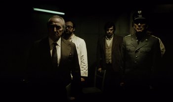 Movie still from “A Short Film About Killing” (1988), directed by Krzysztof Kieslowski – A group of men standing next to each other in a room; Medium shot, Low angle