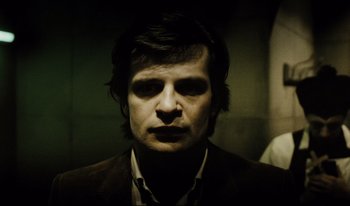 Movie still from “A Short Film About Killing” (1988), directed by Krzysztof Kieslowski – A man in a brown suit and white shirt is looking at the camera; Close Up shot, Low angle