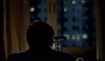 Movie still from “A Short Film About Love” (1988), directed by Krzysztof Kieslowski – A man looking out a window at night; Medium shot, Over the shoulder angle