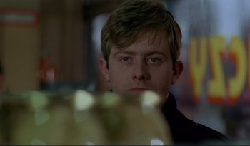 Movie still from “A Short Film About Love” (1988), directed by Krzysztof Kieslowski – A young man is looking into the camera; Close Up shot, Over the shoulder angle