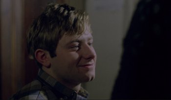 Movie still from “A Short Film About Love” (1988), directed by Krzysztof Kieslowski – A young man with blonde hair smiling for the camera; Close Up shot, Over the shoulder angle