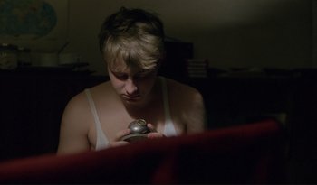 Movie still from “A Short Film About Love” (1988), directed by Krzysztof Kieslowski – A person holding a small metal object in their hands; Close Up shot, High angle