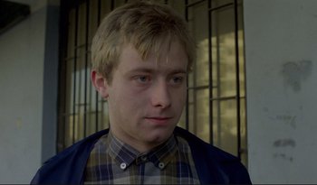 Movie still from “A Short Film About Love” (1988), directed by Krzysztof Kieslowski – A young man in a plaid button up shirt and a blue jacket; Close Up shot, Low angle