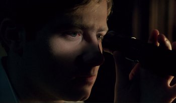 Movie still from “A Short Film About Love” (1988), directed by Krzysztof Kieslowski – A man looking through a microscope in the dark; Extreme Close Up shot, High angle