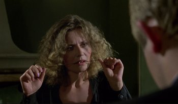 Movie still from “A Short Film About Love” (1988), directed by Krzysztof Kieslowski – A woman with curly hair is holding a stick in her mouth; Close Up shot, Over the shoulder angle