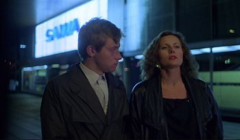 Movie still from “A Short Film About Love” (1988), directed by Krzysztof Kieslowski – A man and a woman standing next to each other on the street; Medium shot, Low angle