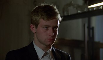 Movie still from “A Short Film About Love” (1988), directed by Krzysztof Kieslowski – A man in a suit and tie looking at the camera; Close Up shot, Over the shoulder angle