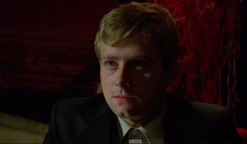 Movie still from “A Short Film About Love” (1988), directed by Krzysztof Kieslowski – A man in a black suit and white tie; Close Up shot, Low angle