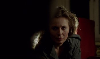 Movie still from “A Short Film About Love” (1988), directed by Krzysztof Kieslowski – A woman is looking at the camera in a dark room; Close Up shot, Over the shoulder angle