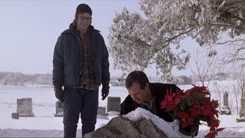 Movie still from “A Simple Plan” (1998), directed by Sam Raimi – A man laying on the ground next to another man; Medium shot, Low angle