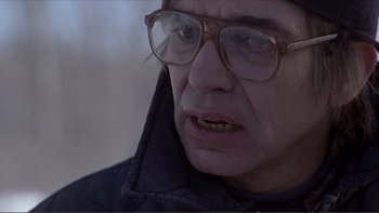 Movie still from “A Simple Plan” (1998), directed by Sam Raimi – An older man wearing glasses and wearing a jacket; Close Up shot, Over the shoulder angle