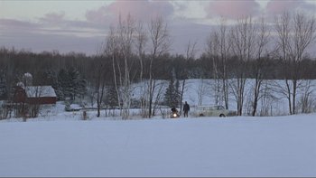 Movie still from “A Simple Plan” (1998), directed by Sam Raimi – A person riding a snowmobile on a snowy field; Extreme Wide shot, High angle