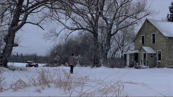 Movie still from “A Simple Plan” (1998), directed by Sam Raimi – A person walking in the snow next to a tree; Extreme Wide shot, Low angle