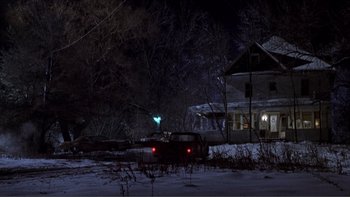 Movie still from “A Simple Plan” (1998), directed by Sam Raimi – A car parked in front of a house at night in the snow; Extreme Wide shot, Low angle