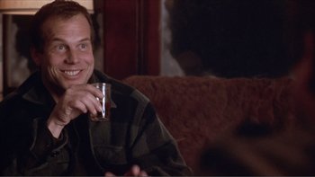 Movie still from “A Simple Plan” (1998), directed by Sam Raimi – A man sitting on a couch holding a cup; Close Up shot, Over the shoulder angle