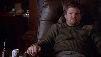 Movie still from “A Simple Plan” (1998), directed by Sam Raimi – A person sitting in a chair wearing a sweater; Medium shot, High angle