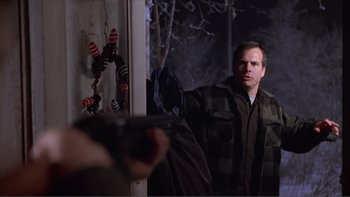 Movie still from “A Simple Plan” (1998), directed by Sam Raimi – A man standing in front of a window holding a gun; Medium shot, Over the shoulder angle