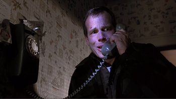 Movie still from “A Simple Plan” (1998), directed by Sam Raimi – A man talking on a phone in a room with tiled walls; Close Up shot, Low angle