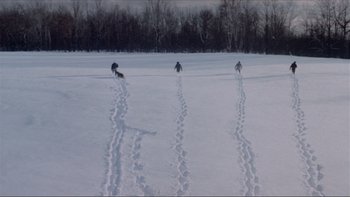 Movie still from “A Simple Plan” (1998), directed by Sam Raimi – A group of people riding skis on top of snow covered ground; Extreme Wide shot, High angle