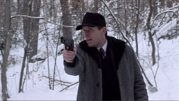 Movie still from “A Simple Plan” (1998), directed by Sam Raimi – A man holding a gun while standing in the snow; Medium shot, Over the shoulder angle