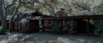 Movie still from “A Single Man” (2009), directed by Tom Ford – An outdoor area with a fireplace and patio furniture; Extreme Wide shot, Low angle