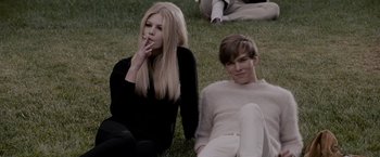 Movie still from “A Single Man” (2009), directed by Tom Ford – Two people sitting in the grass smoking a cigarette; Medium shot, High angle