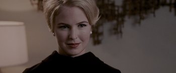 Movie still from “A Single Man” (2009), directed by Tom Ford – A woman with blonde hair wearing a black top; Close Up shot, Over the shoulder angle