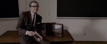 Movie still from “A Single Man” (2009), directed by Tom Ford – A man sitting at a table with a briefcase; Medium shot, Over the shoulder angle