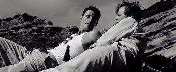 Movie still from “A Single Man” (2009), directed by Tom Ford – A man holding a beer and sitting next to another man; Medium shot, High angle