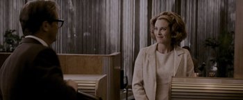 Movie still from “A Single Man” (2009), directed by Tom Ford – A woman in a beige suit standing next to a wooden bench; Medium shot, Over the shoulder angle