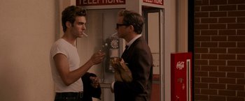 Movie still from “A Single Man” (2009), directed by Tom Ford – Two men standing next to each other in front of a phone booth; Medium shot, Over the shoulder angle