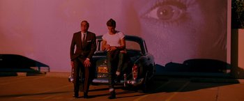 Movie still from “A Single Man” (2009), directed by Tom Ford – Two men sitting on the back of a vintage car; Wide shot, Over the shoulder angle