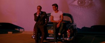 Movie still from “A Single Man” (2009), directed by Tom Ford – Two men sitting on the back of an old car; Medium shot, Over the shoulder angle