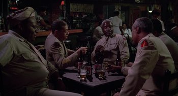 Movie still from “A Soldier's Story” (1984), directed by Norman Jewison – A group of men sitting at a table drinking beer; Medium shot, High angle