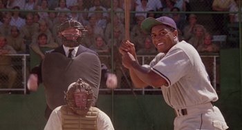 Movie still from “A Soldier's Story” (1984), directed by Norman Jewison – A man holding a baseball bat on top of a baseball field; Medium shot, Over the shoulder angle